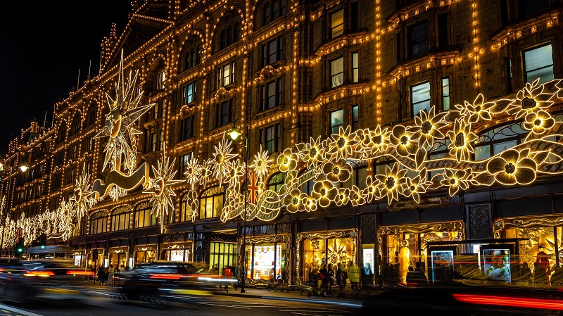Harrods varuhus i London i mrkret. Fasaden glittrande upplyst med julbelysning.